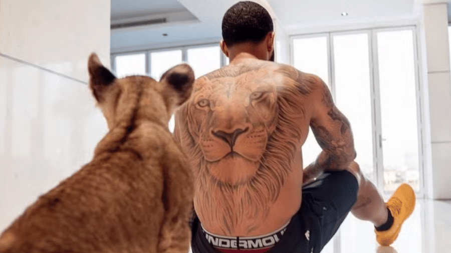 Memphis Depay e o ligre utilizado pelo jogador em um de seus clipes musicais. O atacante foi criticado por usar o animal exótico - Reprodução/Instagram/@y1079fm