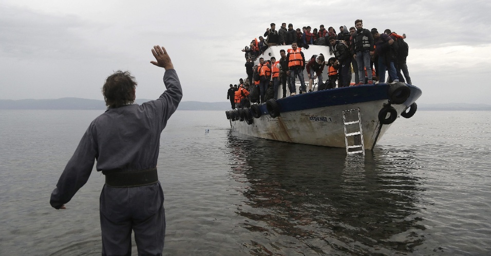 11.out.2015 - Residente da ilha de Lesbos, na Grécia, acena para barco pesqueiro superlotado com refugiados e migrantes que saiu da Turquia