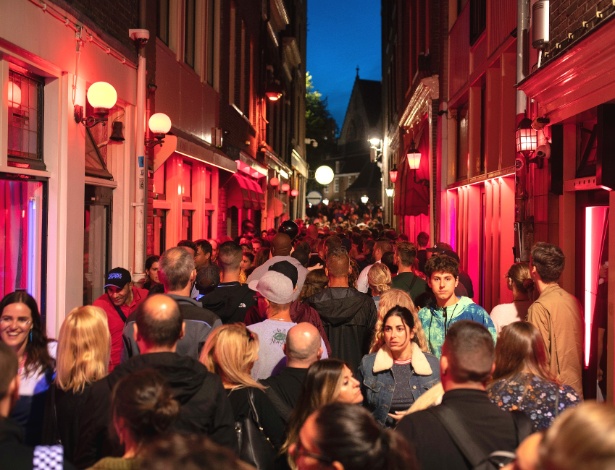 Turistas passeiam por um beco lotado no distrito da Luz Vermelha em Amsterdã - Jasper Juinen/The New York Times