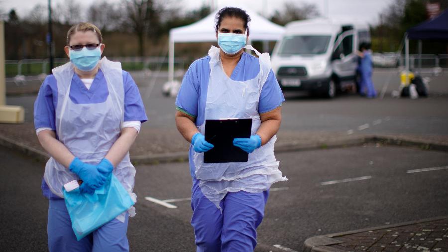 Enfermeiras do NHS esperam o próximo paciente em um passeio pelo local de testes do coronavírus em um estacionamento na Inglaterra - Christopher Furlong/Getty Images