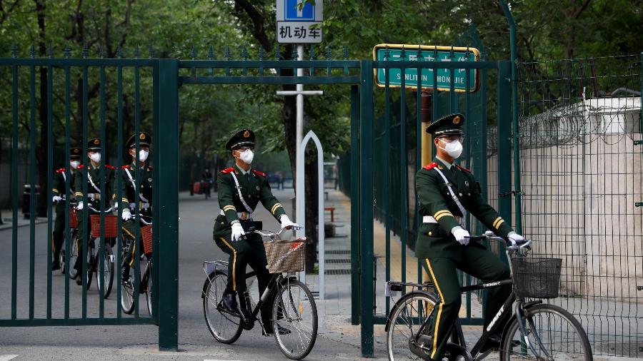 Policiais paramilitares usam máscaras protetoras enquanto andam de bicicleta em Pequim, na China - THOMAS PETER/REUTERS