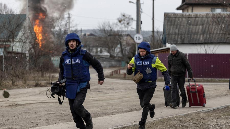 6.mar.2022 - Jornalistas correm para se proteger após bombardeios pesados na Ucrânia - CARLOS BARRIA/REUTERS
