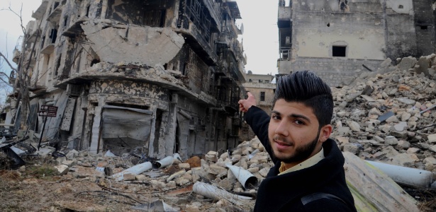 Homem aponta para os destroços do prédio onde morava, em Aleppo, na Síria - Ammar Safarjalany/Xinhua