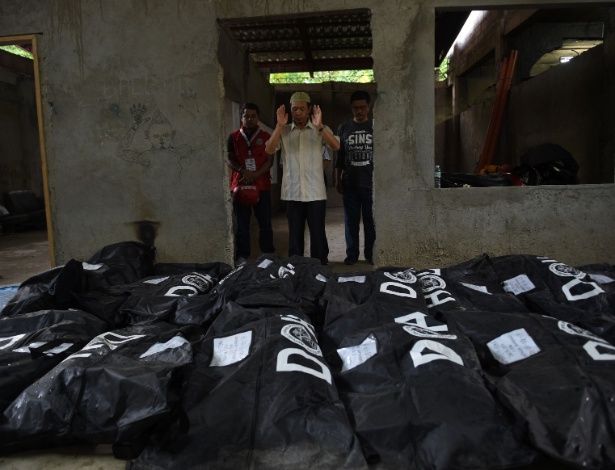 Imã ora em frente a sacos como restos de vítimas do cerco de Marawi antes de enterro - Ted Aljibe/AFP Photo