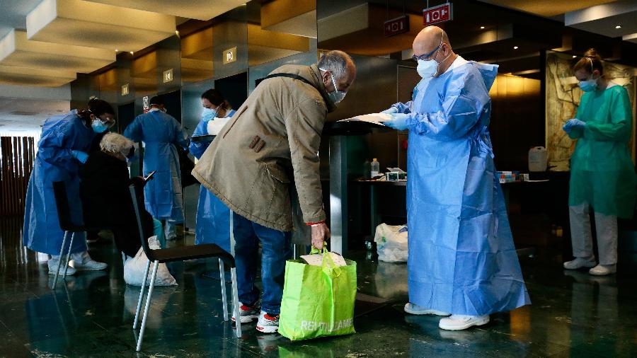 Profissional de saúde recebe paciente que chega ao Hotel Meliá Sarriá - Pau Barrena/AFP