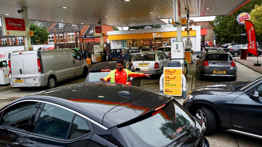 30.set.21 - Um trabalhador guia os carros para o pátio enquanto os veículos fazem fila para reabastecer em um posto de gasolina em Londres, Grã-Bretanha - HANNAH MCKAY/REUTERS