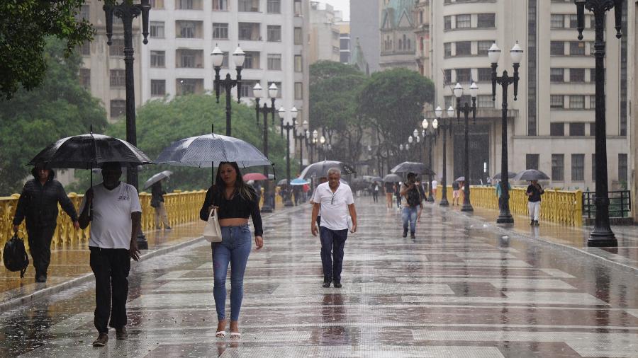 06.nov.24 - Pedestres se protegem da chuva no Viaduto Santa Ifigênia, na região central de São Paulo, na tarde desta quarta-feira (6)