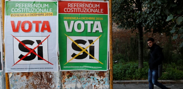 Homem passa por cartazes que apoiam o voto "Sim" no referendo constitucional de domingo, em Roma, na Itália - Tony Gentile/Reuters