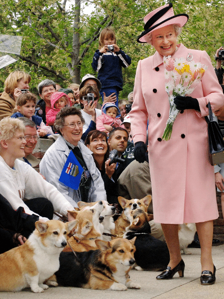 A Rainha Elizabeth II sendo saudada por entusiastas da raça corgi; foto de 2005 - Fiona Hanson - PA Images/PA Images via Getty Images