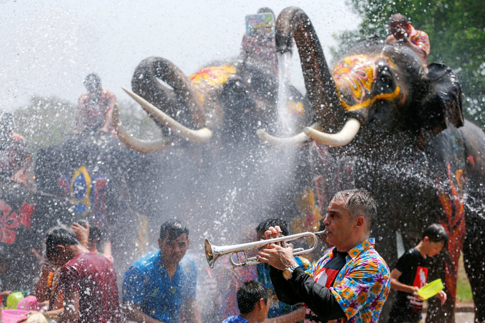 11.abr.2016 - Homem toca trompete enquanto elefantes esguicham água nas pessoas que participam da celebração do Ano-Novo Tailandês na província de Ayutthaya, localizada ao norte da capital Bangcoc - Jorge Silva/Reuters