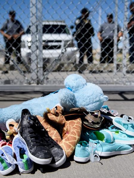 Seguranças parados diante de sapatos e brinquedos deixados para trás no Ponto de Entrada de Tornillo, no Texas, onde os filhos dos imigrantes sem visto foram mantidos após a separação dos pais, em junho - Brendan Smialowski/AFP