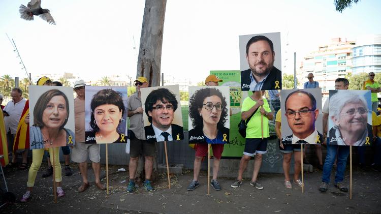 Manifestantes seguram cartazes com as fotos dos líderes catalães presos ou exilados Carme Forcadel, Anna Gabriel, Carles Puigdemont, Marta Rovira, Oriol Junqueras, Jordi Turull e Clara Ponsati durante protesto - Josep Lago/AFP - Josep Lago/AFP