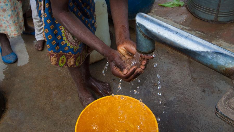 Mulher negra lava as mãos em comunidade pobre - Getty Images