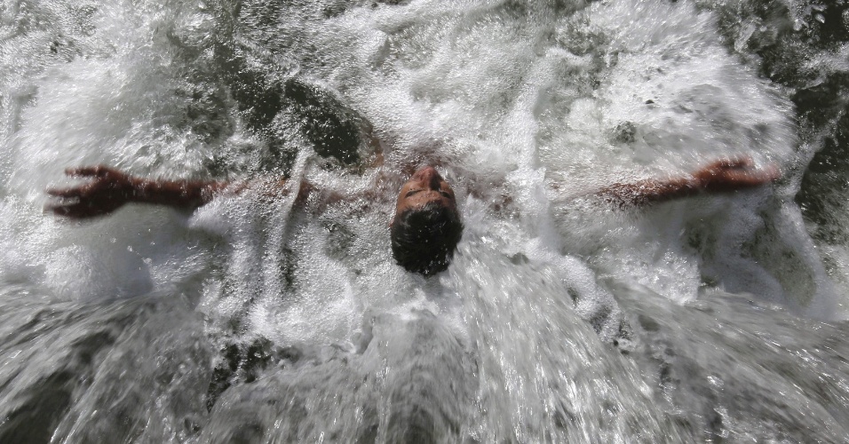 19.ago.2015 - Jovem se refresca em dia calor em Srinagar, na Índia