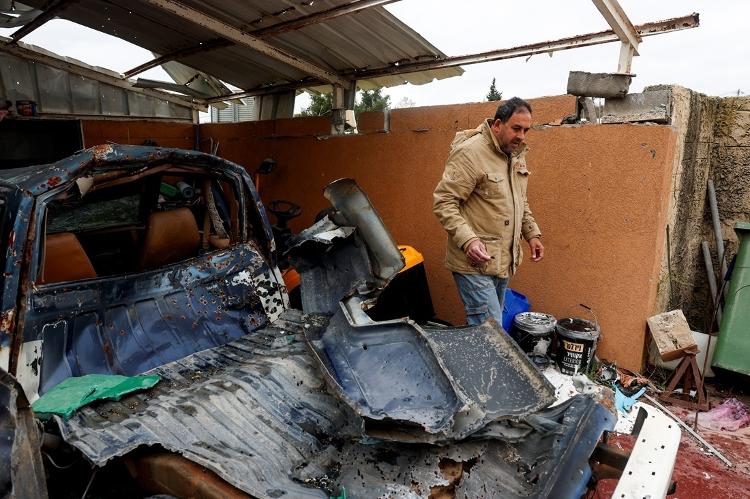 Homem que voltou para casa após cessar-fogo de Hezbollah e Israel checa carro destruído por bombardeios 