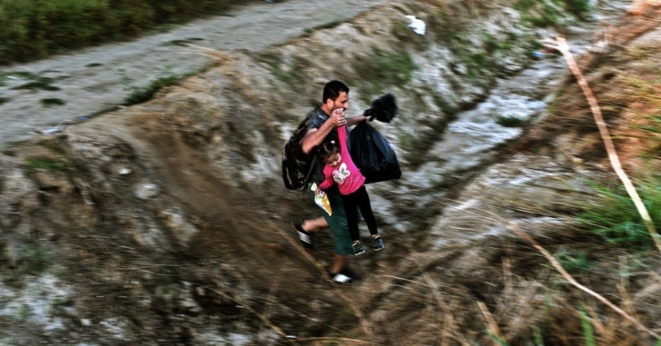 29.ago.2015 - Refugiado carrega sua filha pela mão enquanto cruzam a fronteira da Grécia para a Macedônia, perto da aldeia grega de Idomeni. A União Europeia está enfrentando a pior crise imigratória em 50 anos