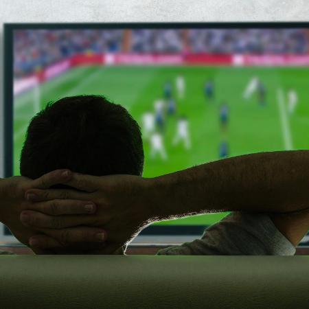 Mais um homem tranquilo vendo futebol na sua televisão