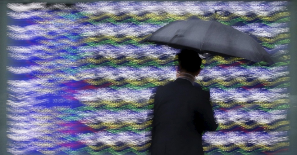 8.set.2015 - Homem olha para um painel eletrônico de uma corretora em Tóquio, no Japão