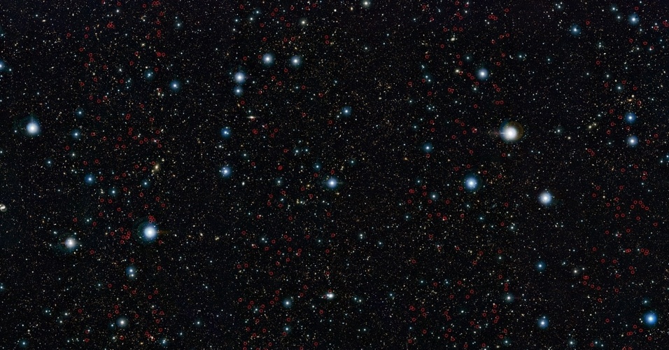 17.nov.2015 - GALÁXIAS DESCOBERTAS - Uma equipe de pesquisadores localizou um grupo de galáxias gigantes que estavam escondidas entre poeira e que existem desde os primórdios do Universo. Na imagem, elas são representadas com pequenos círculos vermelhos. Usando o telescópio VISTA, do ESO (Observatório Europeu do Sul), os astrônomos analisaram desde dezembro de 2009 a mesma região do céu, buscando por essas galáxias, que são muito distantes da Terra e menos brilhantes, ficando pouco visíveis. Com o mapeamento do céu foram encontradas 547 novas galáxias massivas, a maior amostra já reunida deste tipo de galáxia. A descoberta é importante, pois contar galáxias permite que cientistas testem teorias sobre a formação e evolução galática. "Encontramos evidências das galáxias gigantes até cerca de um bilhão de anos após o Big Bang, estamos confiantes que esta é a época em que as primeiras se formaram," conclui Henry McCracken, co-autor do artigo científico que descreve os resultados