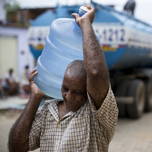 Homem carrega galão de água em Governador Valadares - Fabio Braga/Folhapress