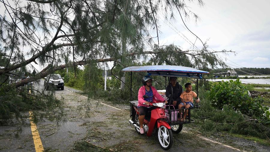 5.jan.2019 - Moradores passam por árvore caída em estrada, rescaldo da tempestade tropical Pabuk na província tailandesa de Nakhon Si Thammarat - Lilian Suwanrumpha/AFP