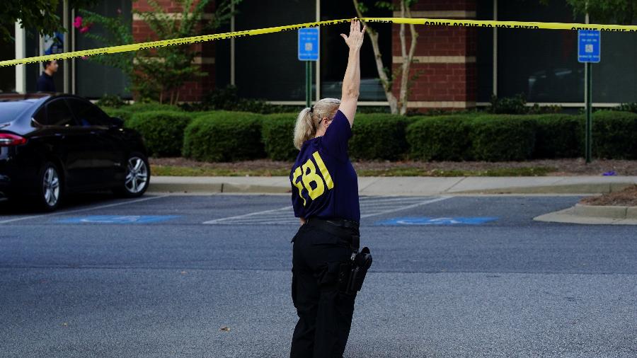 Agente policial nos EUA ajeita faixa em cena do crime - Elijah Nouvelage/Reuters