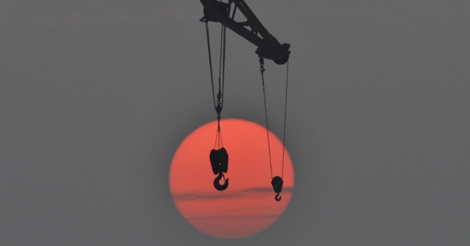 15.out.2015 - Silhueta de guincho de guindaste é registrada durante o amanhecer, no porto de Qingdao, na China