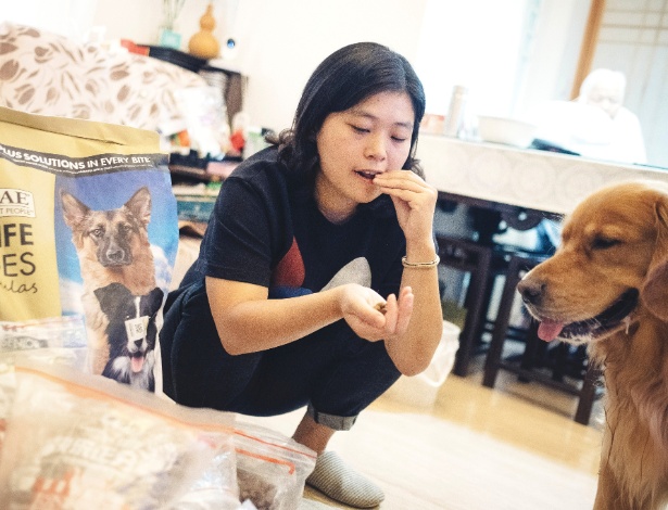 Olivia Ren experimenta ração animal antes de dar para seu cachorro Dada comer, em Xangai, na China - Yuyang Liu/The New York Times