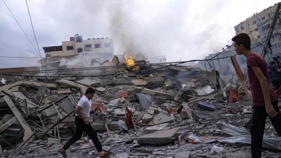 Palestinos nas ruínas de um bairro da Cidade de Gaza, destruído por bombardeios israelenses em 10 de outubro de 2023