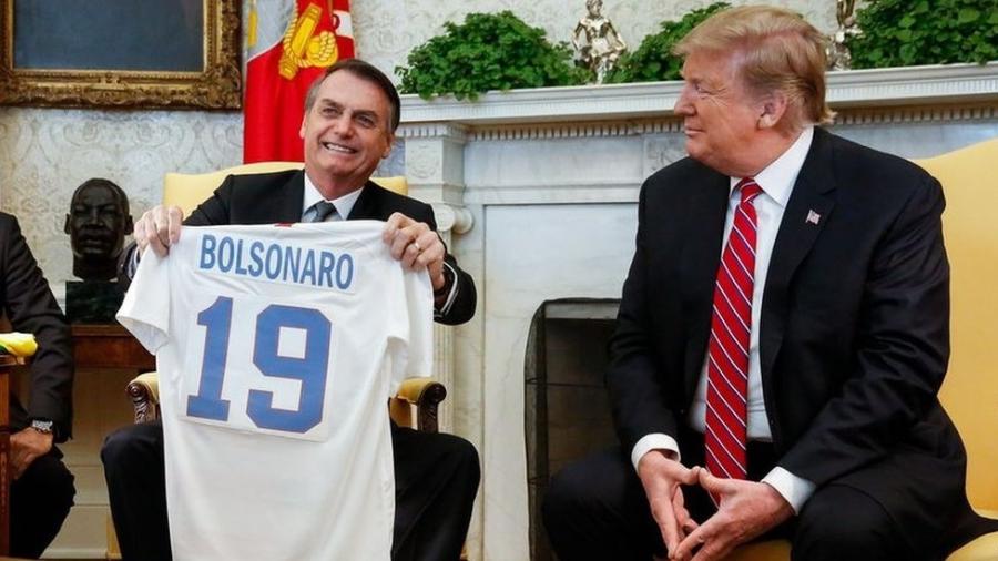 Ao lado de Donald Trump, Jair Bolsonaro segura camisa da seleção dos EUA com o nome dele - Isac Nóbrega/PR