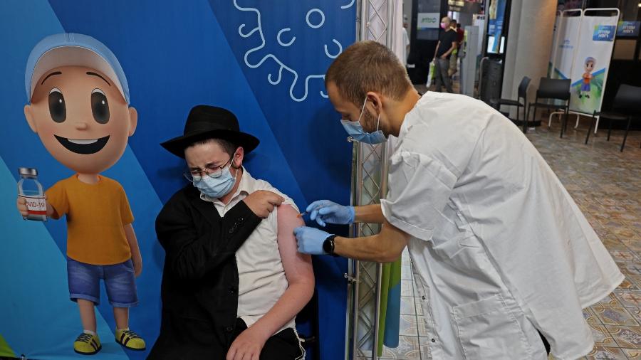 15.ago.2021 - Trabalhador de saúde israelense aplica terceira dose da vacina Pfizer em centro de vacinação em Israel - Menahem Kahana/AFP