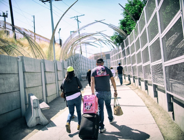 Pedestres caminham em direção ao portão de entrada para o México, na fronteira entre EUA e México, em San Ysidro, na Califórnia - SANDY HUFFAKER/NYT