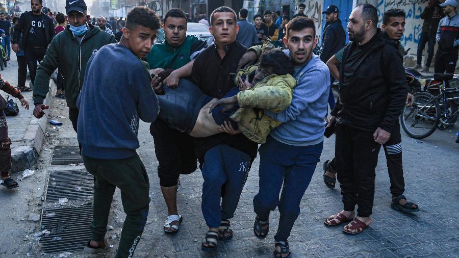 3.dez.2023 - Palestinos carregam homem ferido após ataque de Israel em Rafah, no sul da Faixa de Gaza