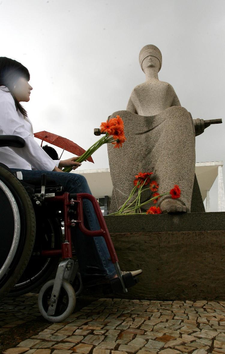 2008: mulher com deficiência deposita flores na estátua da Justiça em ato pela liberação de pesquisas de células-tronco