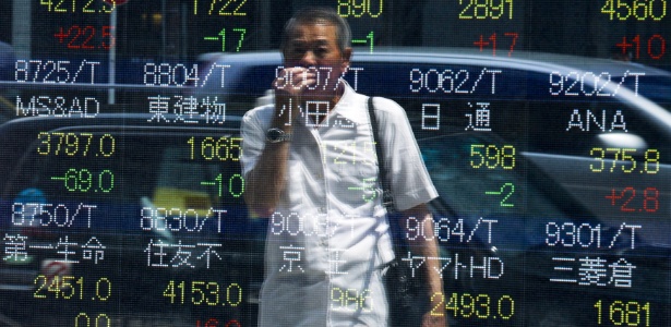 28.jul.2015 - Homem acompanha painel com a cotação de ações da bolsa de valores de Tóquio. O índice Nikkei registrou pequena queda na abertura dos negócios, depois de uma segunda-feira tensa nos mercados devido à forte queda da bolsa da China
