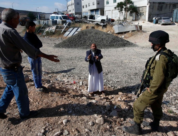 10.jun.2016 - Palestino tenta negociar com soldado israelense na divisa entre as cidades de Hebron e Yatta, na Cisjordânia, onde trropas de Israel limitam a circulação - Hazem Bader/AFP