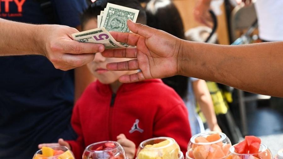 Pessoa paga por frutas em dólares - Getty Images