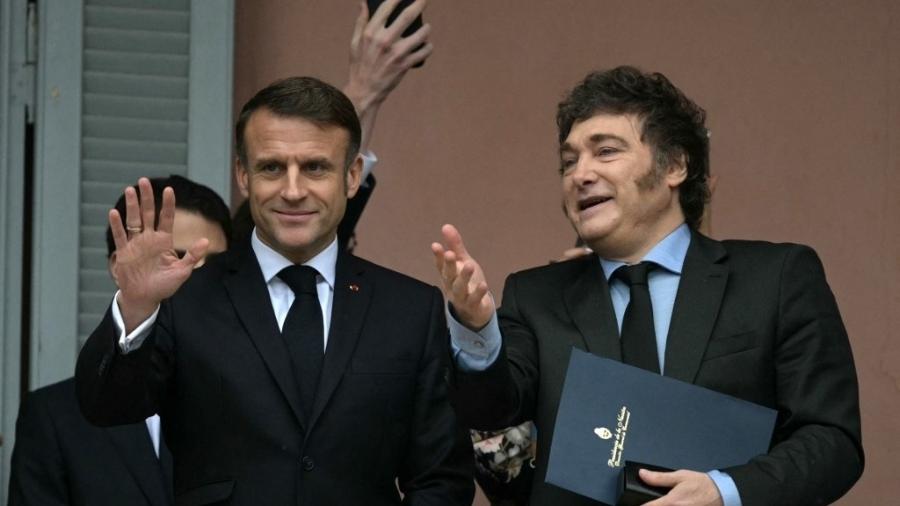 O presidente francês Emmanuel Macron acena ao lado do presidente argentino Javier Milei na sacada do palácio do governo Casa Rosada após uma reunião em Buenos Aires em 17 de novembro de 2024 - JUAN MABROMATA/AFP