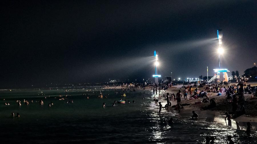 Pessoas se refrescam à noite na praia de Umm Suqeim, em Dubai, nos Emirados Árabes Unidos, no dia de maior calor já registrado para o mês de maio no país Pessoas se refrescam à noite na praia de Umm Suqeim, em Dubai, nos Emirados Árabes Unidos, no dia de maior calor já registrado para o mês de maio no país