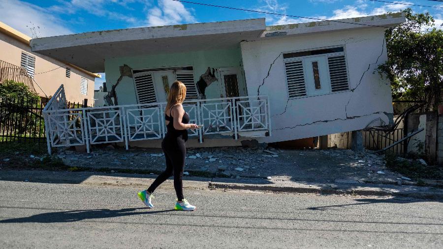 06.jan.2020 - Mulher passa por rua onde casas ficaram destruídas após um tremor na cidade de Guanica, em Porto Rico - Ricardo Arduengo/AFP