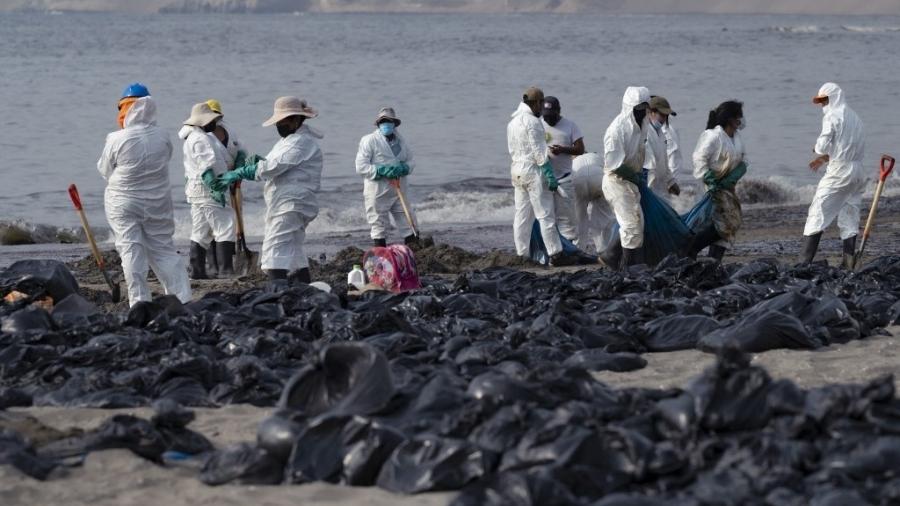 20.jan.2022 - Equipes de limpeza trabalham para remover óleo de uma praia anexa à cidade turística de Ancon, no norte de Lima, no Peru, após um vazamento ocorrido durante o processo de descarga do navio-tanque de bandeira italiana - Cris BOURONCLE / AFP