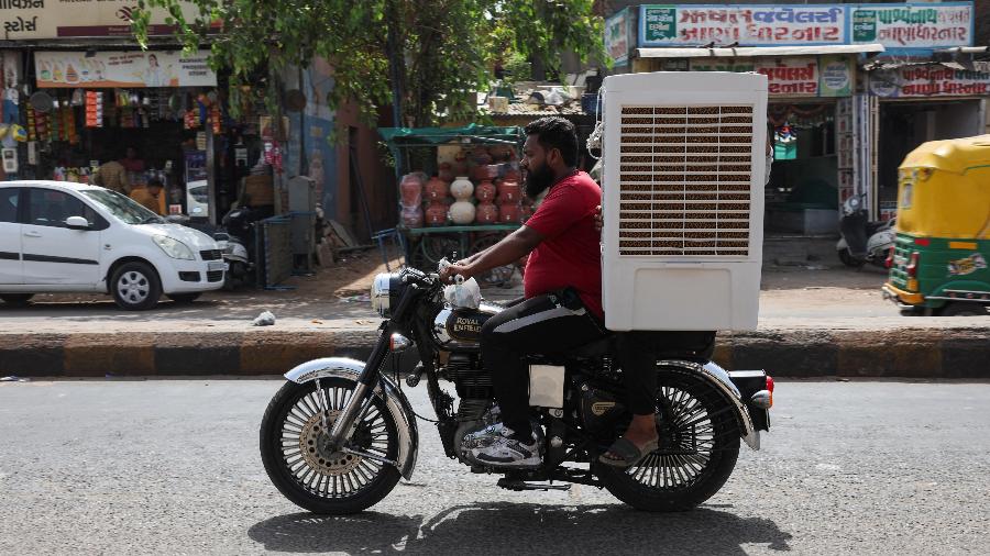 Um homem transporta um refrigerador de ar em uma motocicleta durante uma onda de calor em Ahmedabad, Índia, 30 de maio de 2024