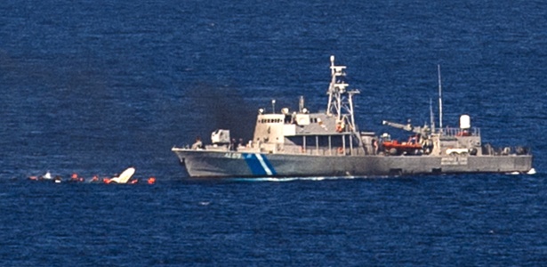 Barco de madeira carregando refugiados (esq) afunda após colidir com embarcação da Guarda Costeira da Grécia próximo à ilha de Lesbos - Dimitar Dilkoff/AFP