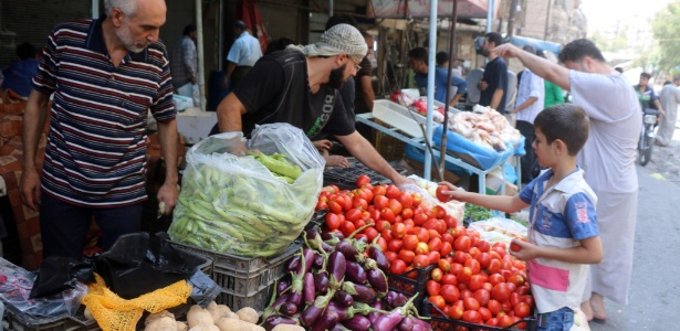 Comerciante vende legumes em mercado em Aleppo, Síria - Thaer Mohammed/ AFP