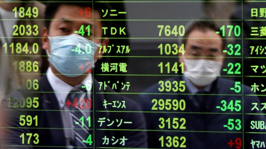 Pedestres observam índices na Bolsa de Tóquio - ISSEI KATO
