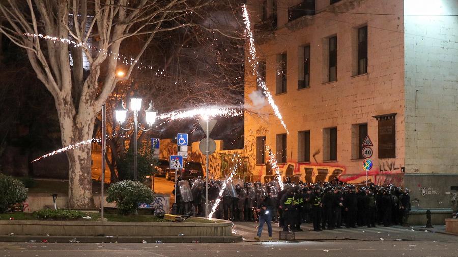 Fogos de artifício explodem perto de policiais durante protesto contra um projeto de lei sobre "agentes estrangeiros" em Tbilisi, na Geórgia - Irakli Gedenidze/Reuters