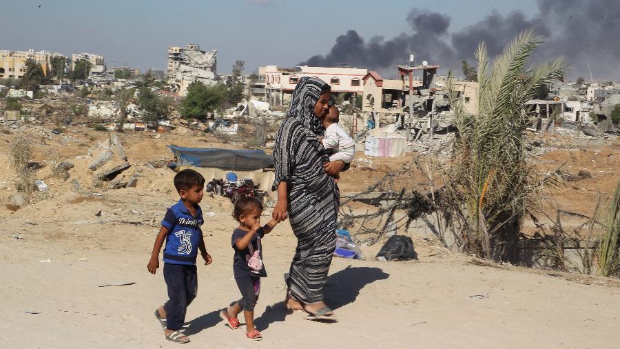 16.ago.2024 - Mulher palestina caminha com os filhos em Khan Younis, em Gaza - Hatem Khaled/Reuters