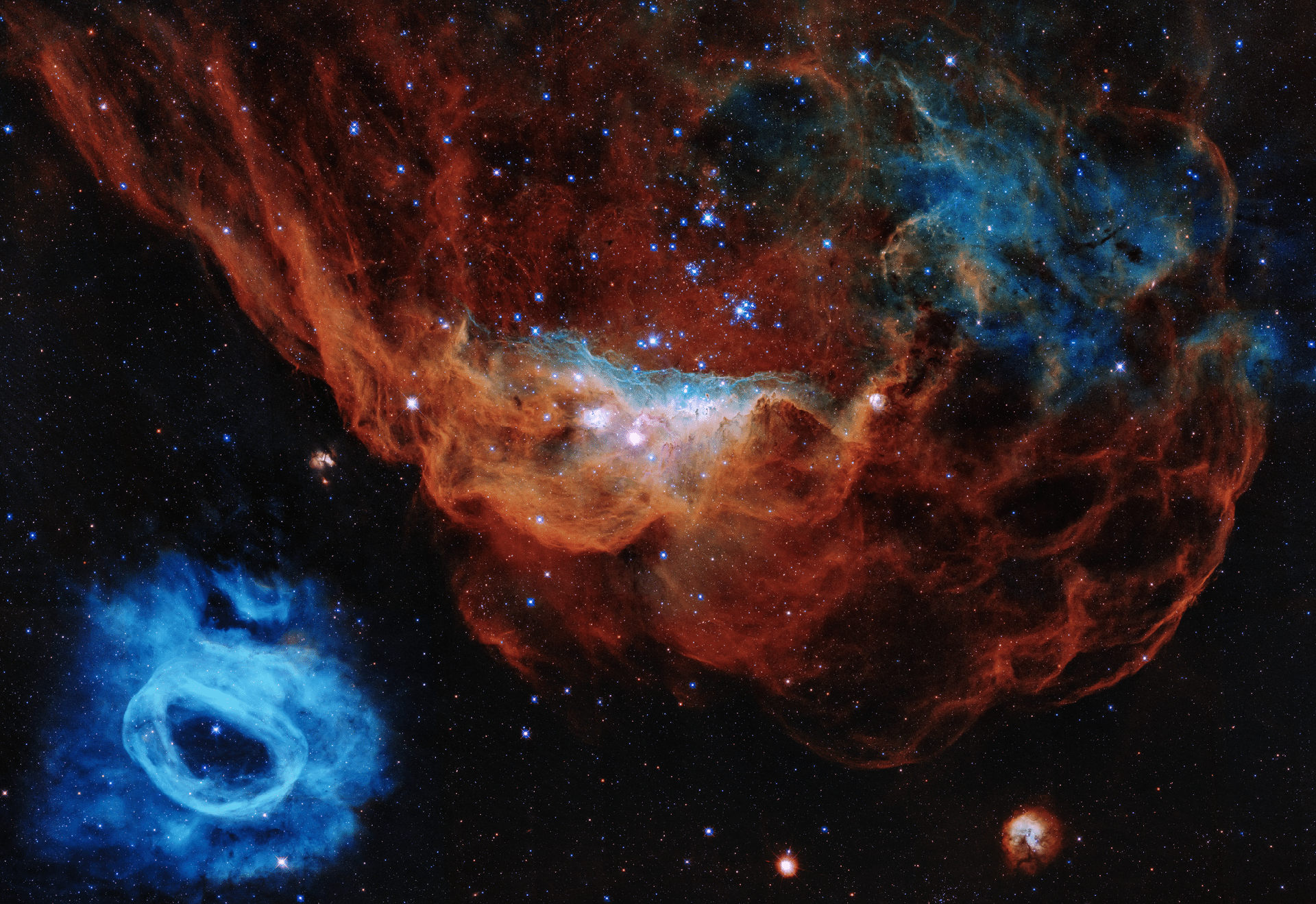 2020 - A nebulosa vermelha gigante (NGC 2014) e seu menor vizinho azul (NGC 2020) fazem parte de uma vasta região de formação de estrelas na Grande Nuvem de Magalhães, uma galáxia satélite da Via Láctea, localizada a 163 mil anos-luz de distância. A imagem é apelidada de "Recife Cósmico", porque segundo a equipe do Hubble, se parece com um mundo submarino. - NASA