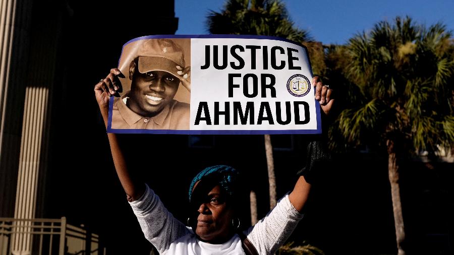 Mulher segura cartaz pedindo justiça por Ahmaud Arbery, homem negro morto em 2020, do lado de fora de tribunal na Geórgia, nos EUA - Marco Bello/Reuters