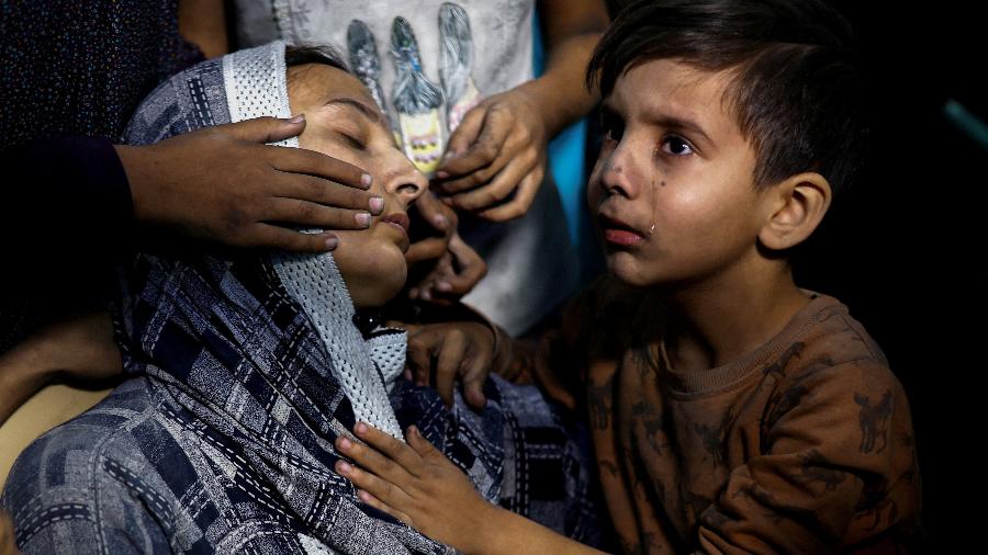 Criança palestina chora ao lado da mãe após ataque israelense, em Khan Younis, no sul da Faixa de Gaza